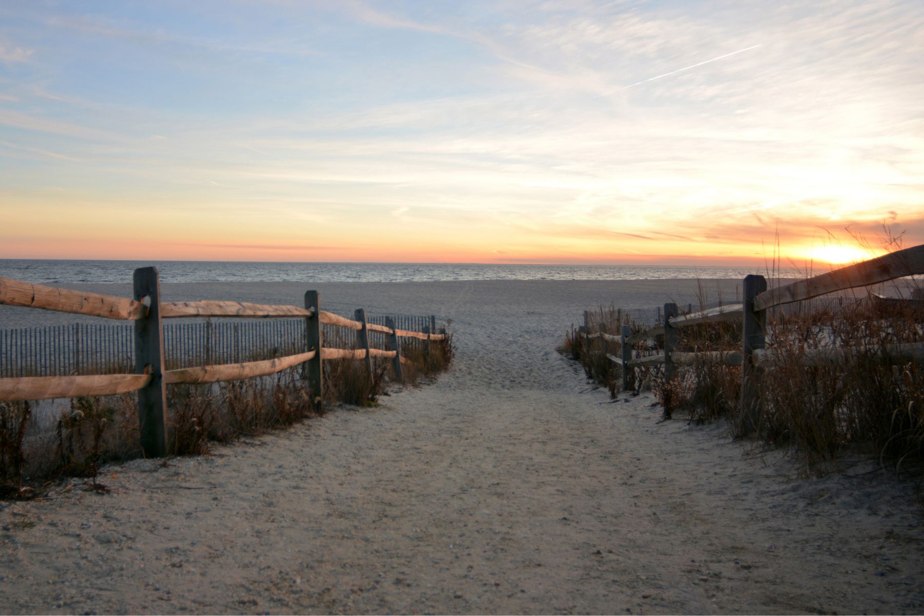 Sunset over a beach path and dune fence on the New Jersey shore